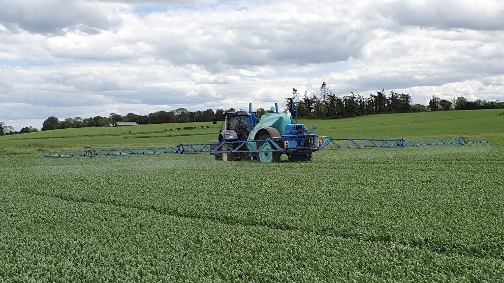 Tractor and sprayer in a field of wheat